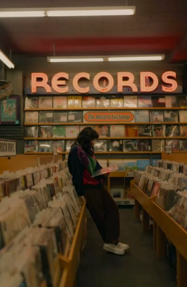 A woman standing in an old vintage records store, looking at vinyls.