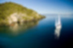 Sail Barbary Eco Tours cruising toward Māori Rock Carvings on Lake Taupō, New Zealand – surrounded by calm blue water, kayakers, and native bush-clad cliffs