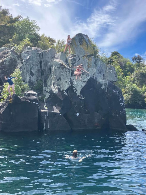 People jumping off rocks into blue water