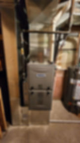 Modern gas furnace unit with metal ductwork in a basement