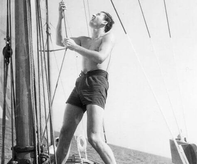 Man adjusting sailboat rigging at sea
