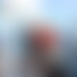 Family smiling on a sailboat with a child and dog, surrounded by open water under a clear blue sky.