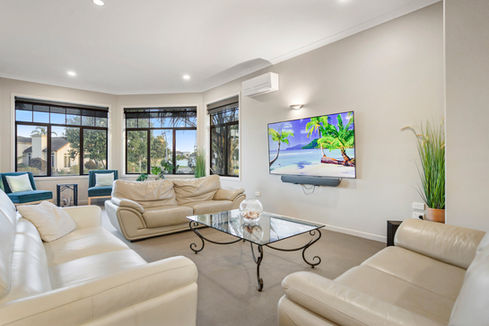 Spacious living room with beige sofas, TV, and large windows IN HAUS.