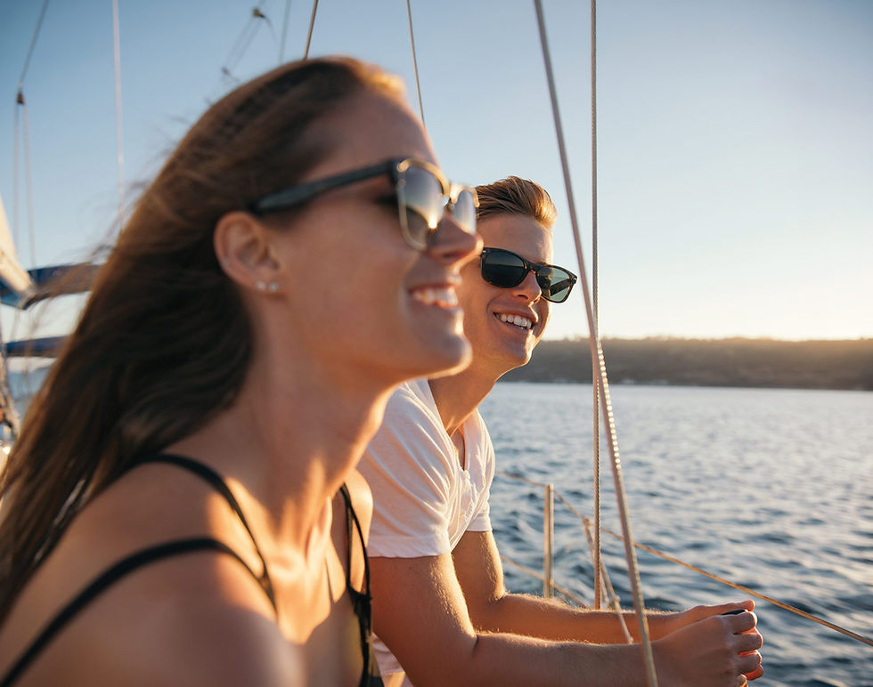 A smiling couple wearing sunglasses on the Sail Barbary boat cruise at sunset