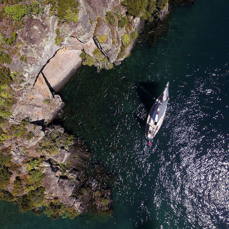 Aerial view of the Sail Barbary boat anchored near a rocky cliff.