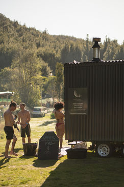 People near a dark shed with sign outdoors IN HAUS and a natural setting