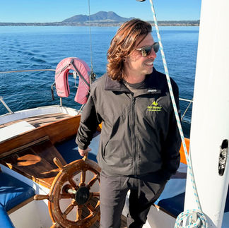 Sail Barbary skipper standing at the helm of an eco sailing yacht on Lake Taupō during an authentic sailing cruise.