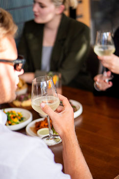 Man holding up wine glass, dining with friends at a restaurant IN HAUS.