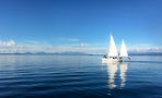 Sail Barbary electric yacht cruising on calm Lake Taupō with passengers on deck and mountains on the horizon, New Zealand
