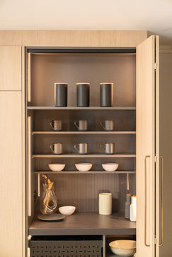 Open kitchen cabinet with organized dishware and canisters INSPACE CABINETRY.