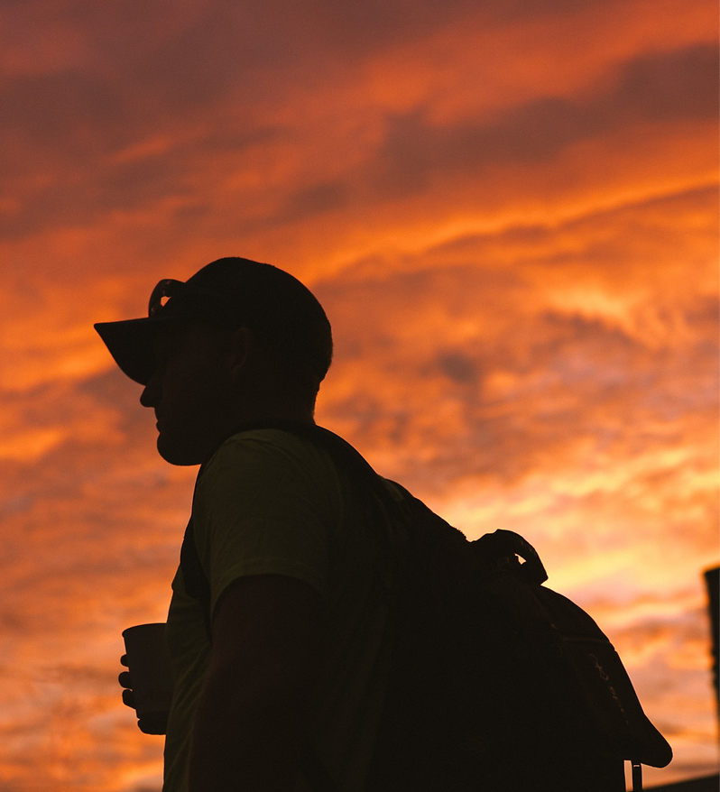 a man in work gear in front of a sunrise