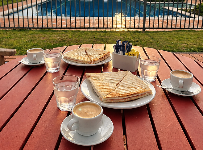 Desayuno tranquilo junto a la piscina al atardecer.png