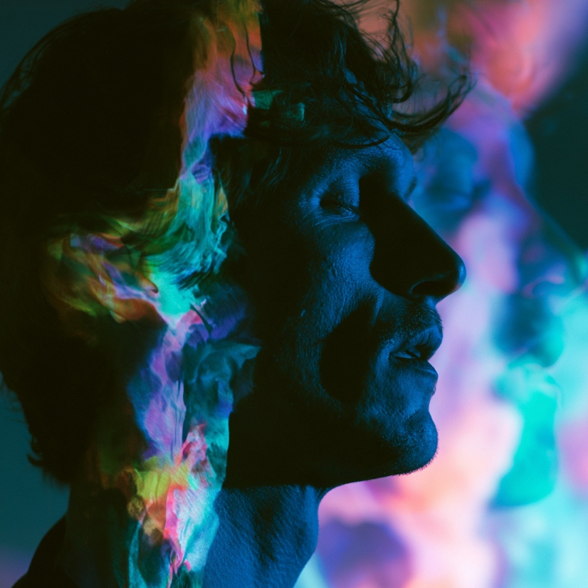 Man with colorful light patterns projected on his face.