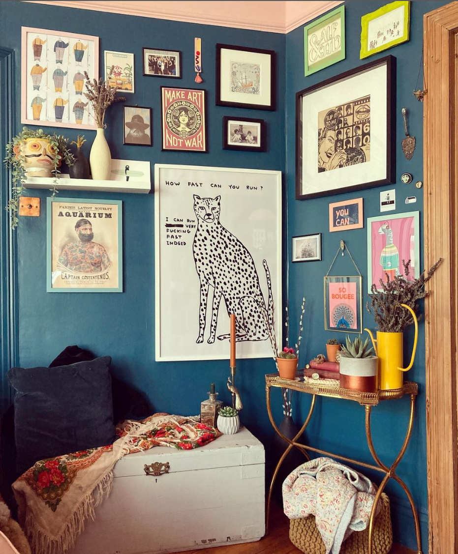 Maximalist interior design, maximalist gallery wall, period property, Edwardian home, art wall. Dark blue living room. Eclectic art display- leopard, tattooed man, 60s lino print, fishermen, art not war, so bougee, family photos, black and white lino