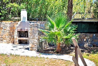 Traditional stone BBQ and outdoor grilling station set within the lush gardens of the Crete vacation rental.