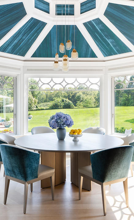 Luxury Old Westbury kitchen and dining area with plush seating, round dining table, statement ceiling wallpaper and cascading pendant lighting
