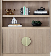 Custom oak bookcase with brass semi-circle Luna pulls and layered decorative accessories — modern living room detail by Bespoke Design NY, Port Washington.