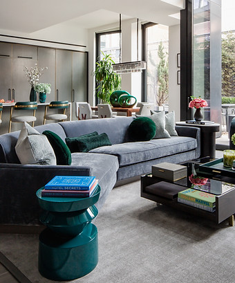 Modern NYC living room with angled sectional in grey velvet and green details