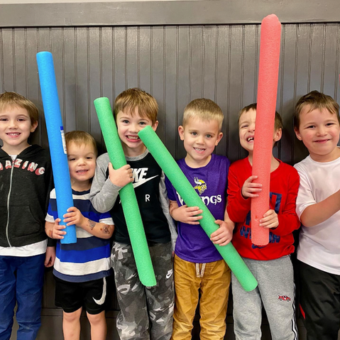 Young kids with pool noodles at karate gym