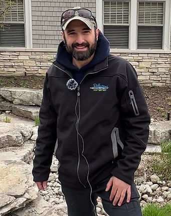 Man with microphone wearing a hat at a pond location.