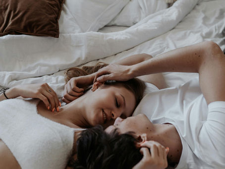 זוג שוכב במיטה ברגע אינטימי 