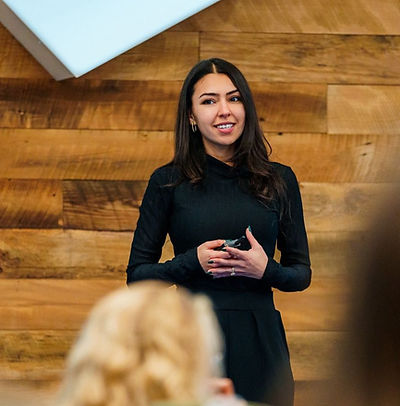 Maya Isharani leading a workshop, speaking to a seated audience