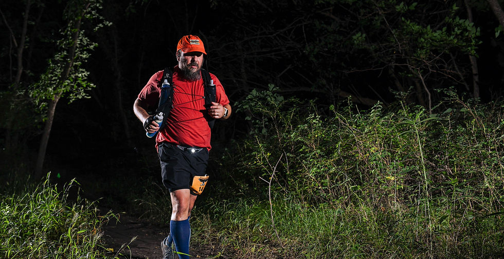 Erin Doom running alone on a wooded trail during the NightHawk ultramarathon at night.