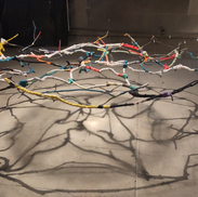 Installation suspendue présentant un rhizome de tissus en lévitation dans une lumière venue du plafond.