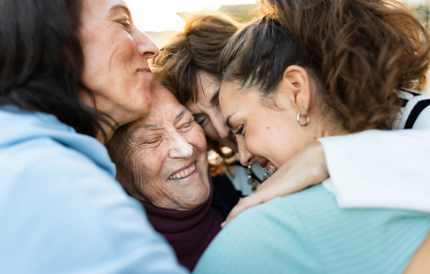 Photograph of four women of varying ages, hugging altogether, smiles on their faces.
