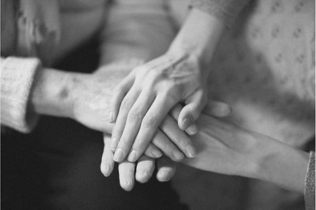 Black & white photograph of two sets of hands, stacking on top of one another.