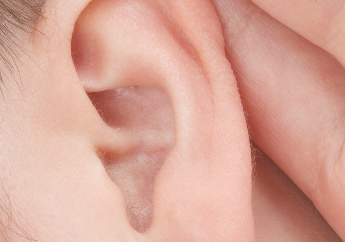 Close-up of a person's ear and finger