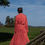 Thumbnail: girl showing back of red silk dress in park next to brown broken fence