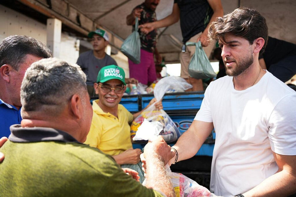 Davi Brandão entrega alimentos a morador durante a ação da Rota Solidária, na Semana Santa.