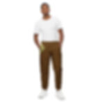 A man wearing brown long pants with his right hand in pocket and white T-shirt facing forward