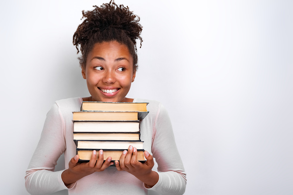 Black girl carrying textbooks in her hands.