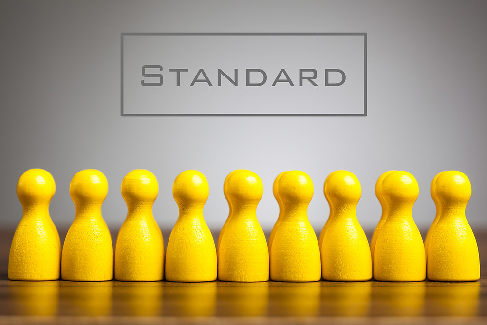 A row of yellow wooden pegs all look the same with the word Standard written on top.
