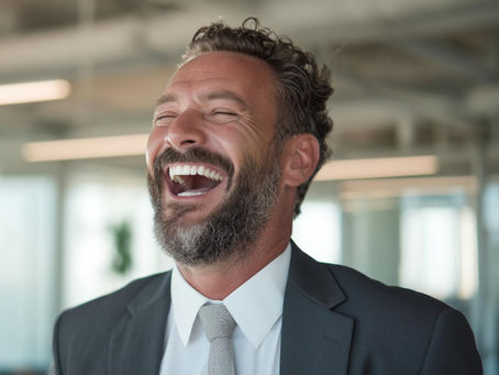 Lachender Mann im Anzug in modernem Büro – Humor als Führungsinstrument für positive Unternehmenskultur und motivierende Mitarbeiterführung