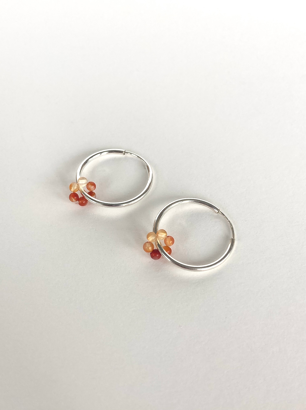 sterling silver hoops with carnelian beads hand-strung in a loop dangling off of hoops