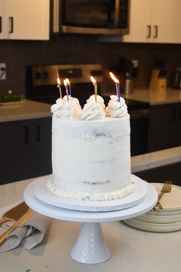 Putting candles on a confetti layer cake with vanilla custard and vanilla buttercream.