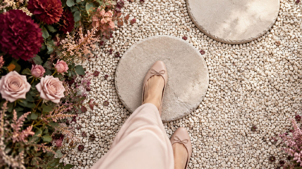 Füße in hellen Ballerinas betreten den ersten Trittstein eines Gartenwegs als Bild für den nächsten Schritt