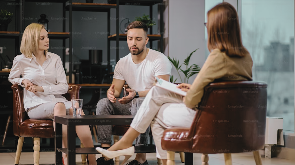 A couple speaking in a therapist's office while a couples therapist sits in front of them. 
