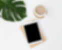 Tablet on desk with coffee and monstera leaf; white, minimalist