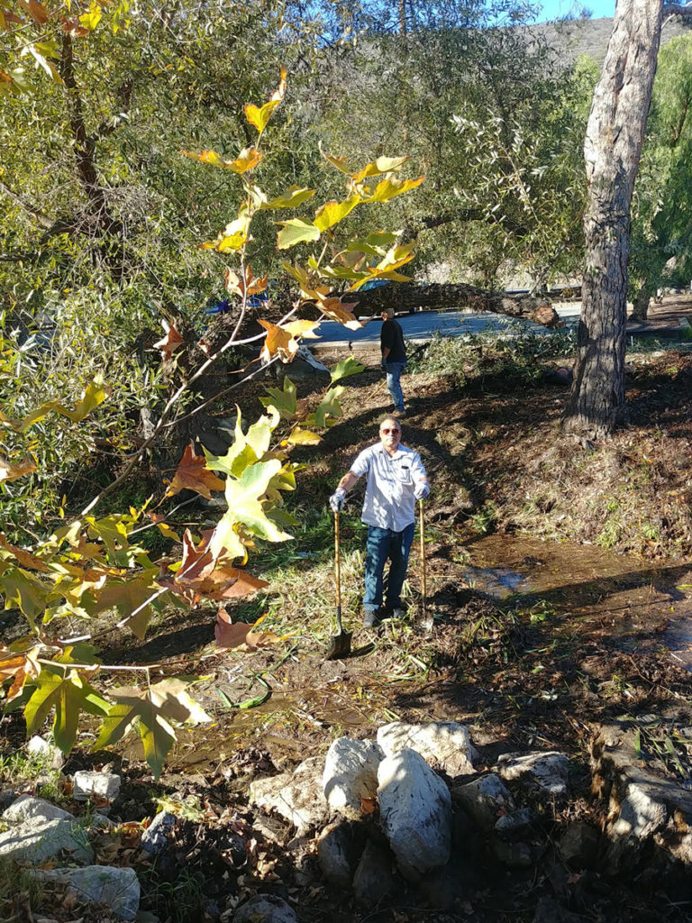 Canyon Club member posing with shovels near a stream