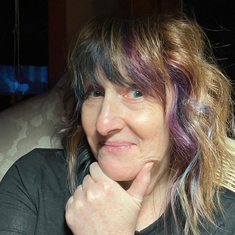 Woman with purple highlights, thoughtful expression