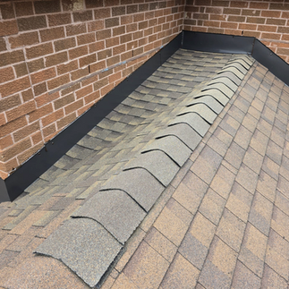 Finished roof ridge cap installed on an asphalt shingle roof in Oshawa with clean metal flashing along the brick wall