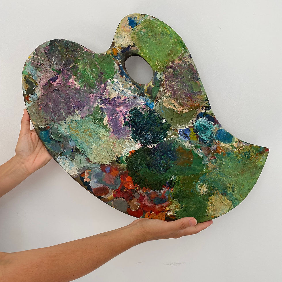 Thumbnail: Vintage wooden artist's palette laden with with many shades and textures of oil paint, particularly green and purples