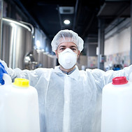 industrial-worker-with-protective-mask-white-uniform-holding-plastic-cans-chemical-industr