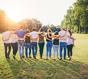 A group of people walking with their arms wrapped around each other