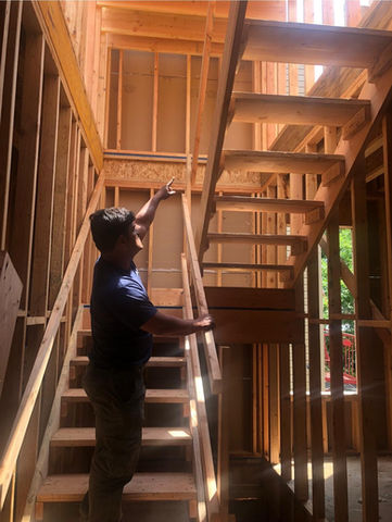 Julio inspecting wooden staircase construction site.