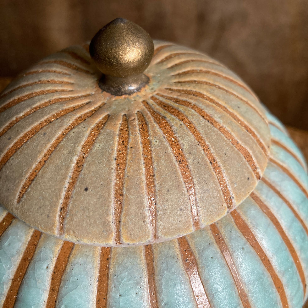 Close up of striped stoneware lid in turquoise crackle glaze with antique bronze gold finial detailing 